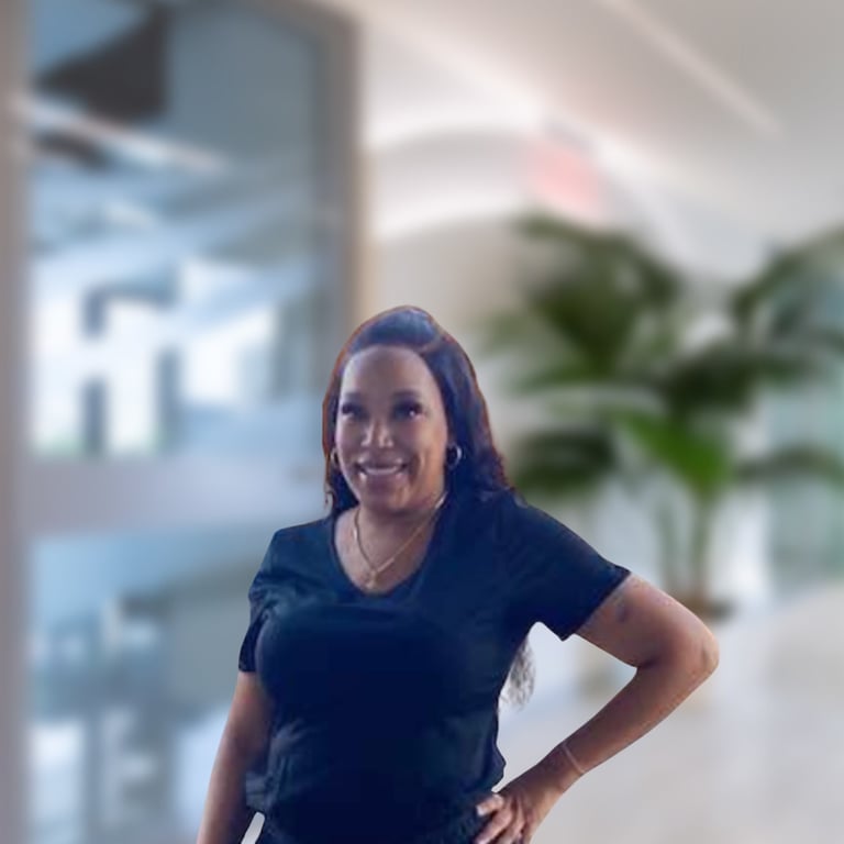 Professional woman in dark blue t-shirt smiling with hand on hip in modern office setting with plants and windows